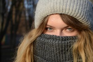 young woman in winter hat with scarf pulled over her face
