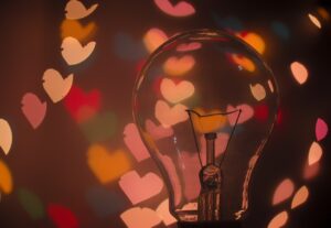 clear light bulb on dark background with hearts