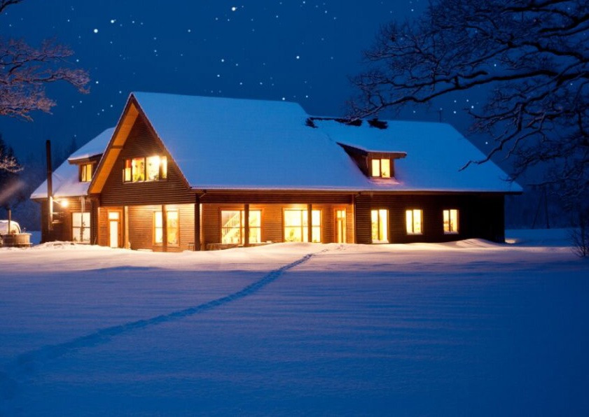 Home surrounded by snow with lights on